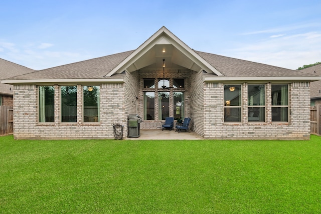 rear view of house featuring a yard, brick siding, a patio area, and fence