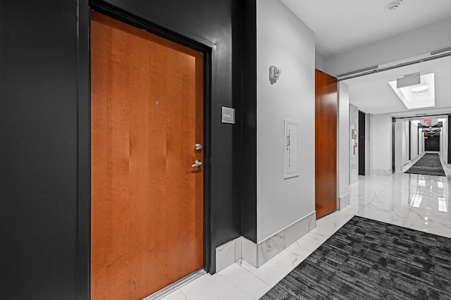 hallway with marble finish floor and baseboards