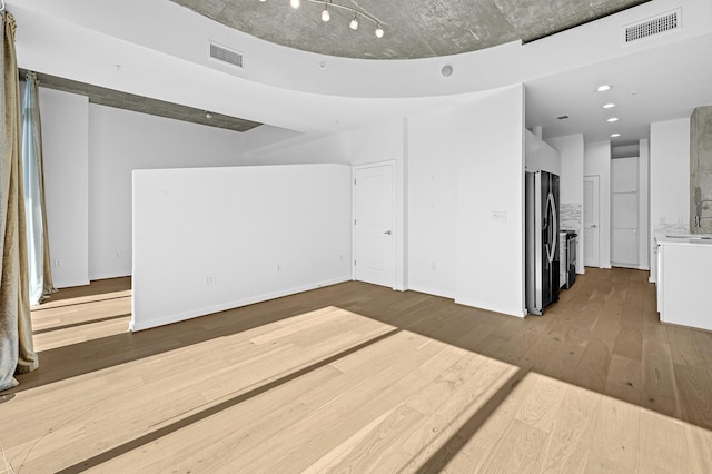 unfurnished living room featuring a sink, dark wood finished floors, visible vents, and baseboards