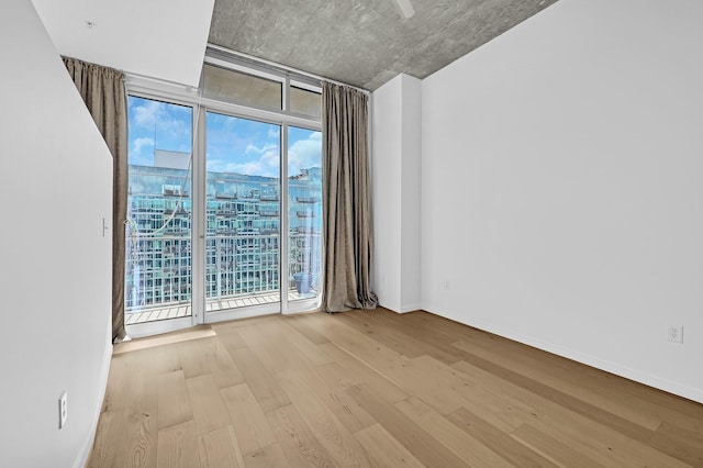 unfurnished room with baseboards, floor to ceiling windows, and wood finished floors