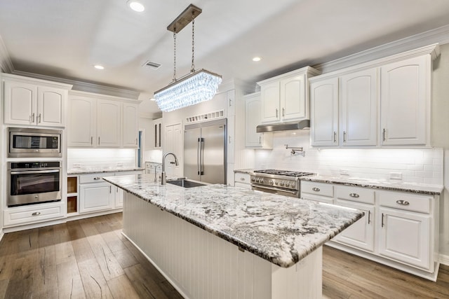 kitchen with visible vents, a sink, hardwood / wood-style flooring, white cabinets, and built in appliances