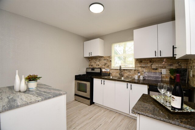 kitchen featuring stainless steel gas range, tasteful backsplash, white cabinetry, and a sink