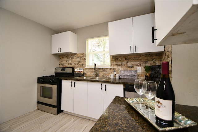 kitchen with light wood-style flooring, a sink, white cabinetry, decorative backsplash, and gas stove