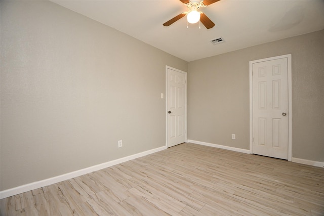 unfurnished room with light wood-style flooring, a ceiling fan, visible vents, and baseboards