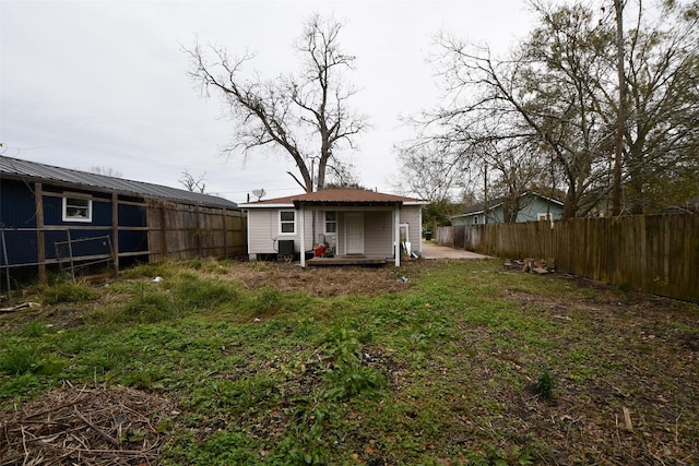 back of property featuring fence, metal roof, and an outbuilding