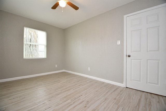 empty room featuring light wood-type flooring, a ceiling fan, and baseboards