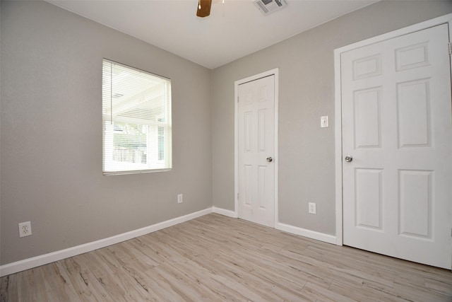 unfurnished bedroom featuring a ceiling fan, light wood-type flooring, visible vents, and baseboards