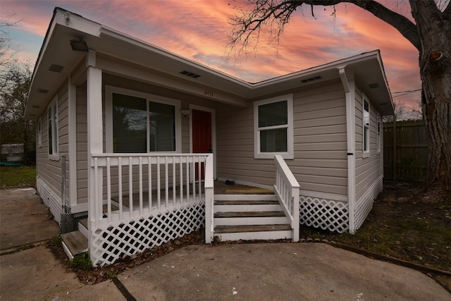 bungalow featuring covered porch and fence