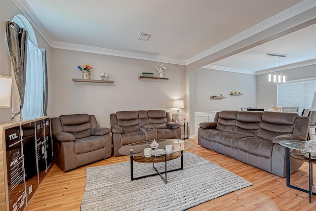 living room with light wood-style floors, visible vents, and ornamental molding