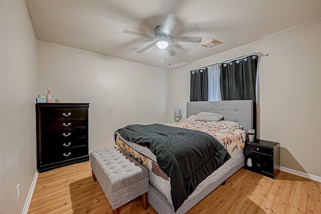 bedroom featuring baseboards, a ceiling fan, visible vents, and light wood-style floors