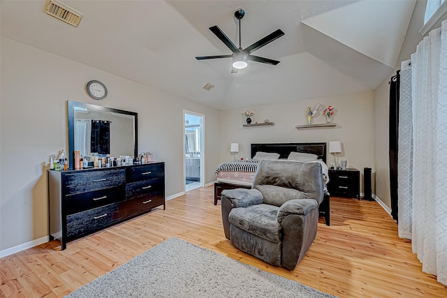 bedroom featuring visible vents, vaulted ceiling, ensuite bath, wood finished floors, and baseboards