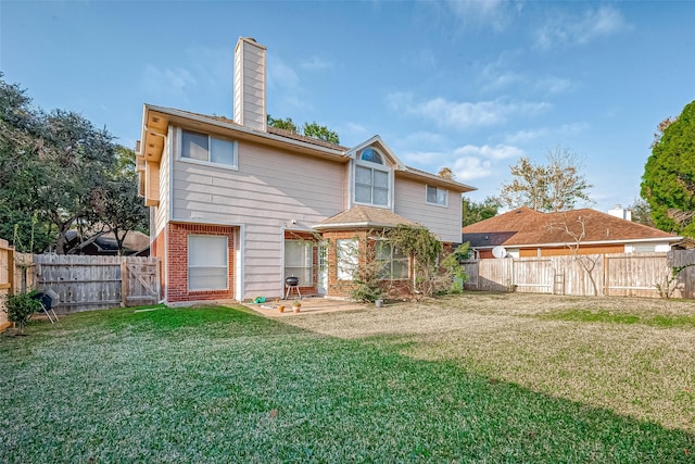 rear view of house with a fenced backyard, a chimney, a lawn, and brick siding