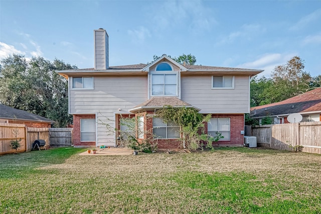 rear view of property with a fenced backyard, a chimney, a lawn, and brick siding