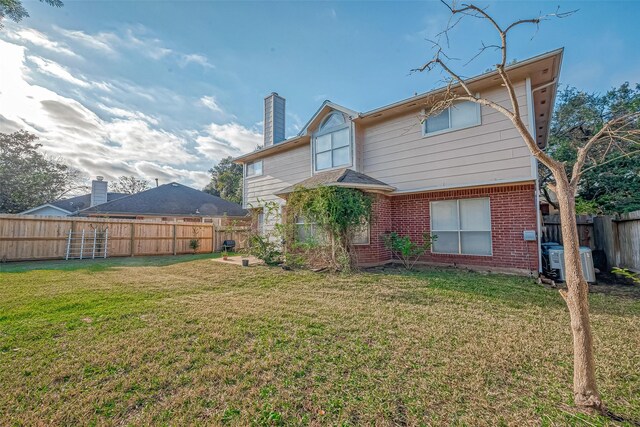 back of house with a fenced backyard, central AC, brick siding, a yard, and a chimney