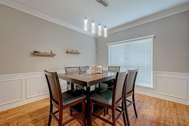 dining area featuring ornamental molding, wainscoting, and light wood-style flooring