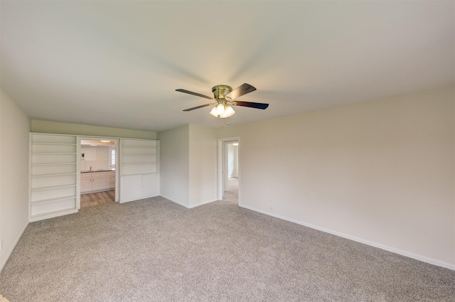 unfurnished bedroom with baseboards, ceiling fan, ensuite bathroom, and light colored carpet