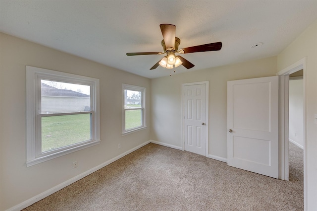 unfurnished bedroom featuring carpet, baseboards, ceiling fan, and a closet