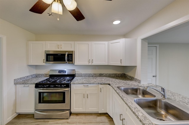 kitchen with white cabinets, light wood finished floors, stainless steel appliances, and a sink