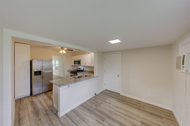 kitchen with light wood-style flooring, stainless steel appliances, a peninsula, baseboards, and light stone countertops