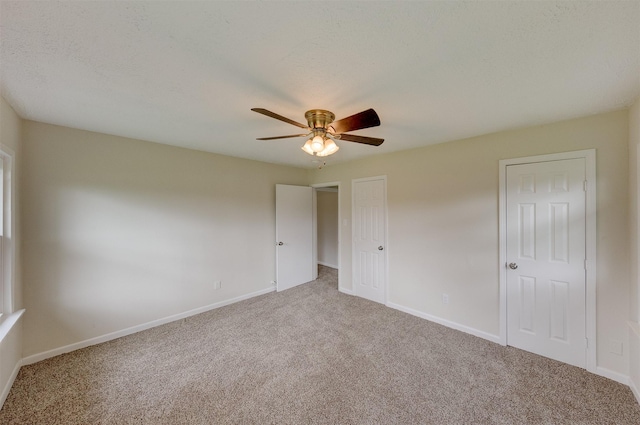 unfurnished bedroom with carpet floors, a textured ceiling, baseboards, and a ceiling fan