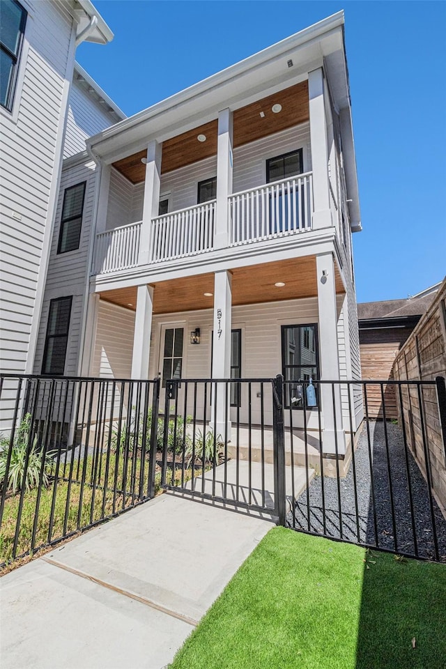 view of front of property featuring covered porch, fence, and a balcony