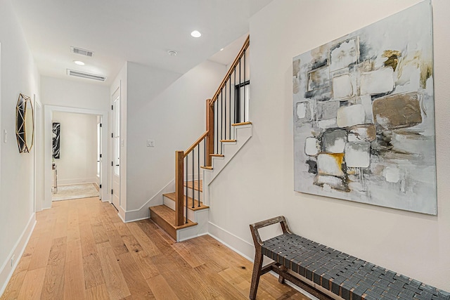hallway with light wood-style floors, baseboards, and visible vents