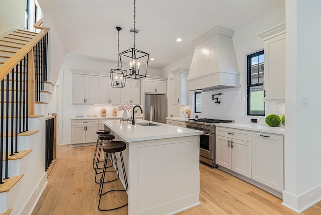 kitchen featuring custom range hood, light wood-style floors, white cabinets, a sink, and high quality appliances