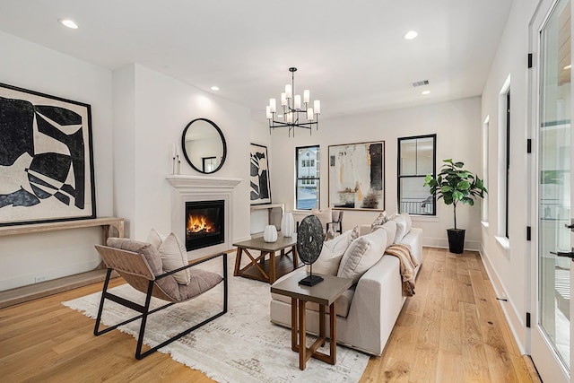 living room with recessed lighting, light wood-style flooring, visible vents, and a glass covered fireplace