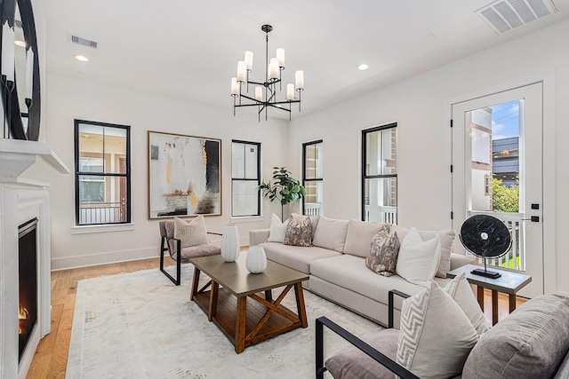 living area with light wood-type flooring, visible vents, a fireplace, and recessed lighting