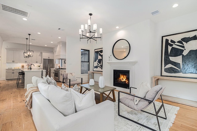 living area featuring light wood-style floors, recessed lighting, visible vents, and a notable chandelier