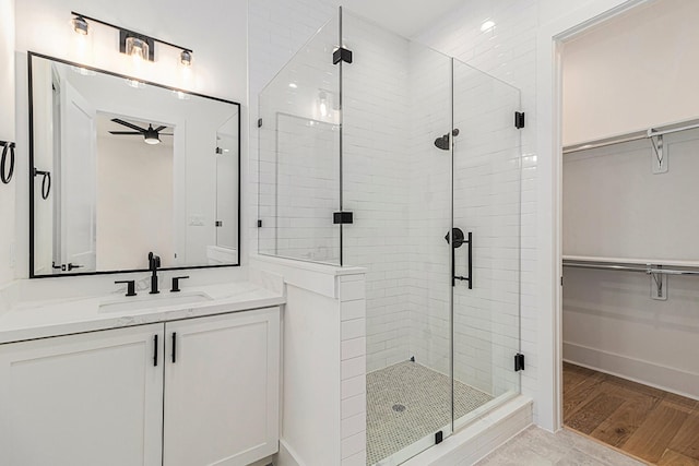 bathroom featuring a shower stall, a spacious closet, baseboards, and vanity