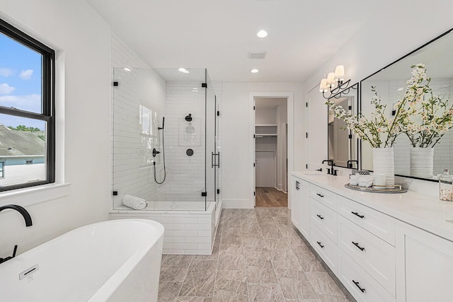 bathroom featuring a stall shower, a soaking tub, a healthy amount of sunlight, and vanity