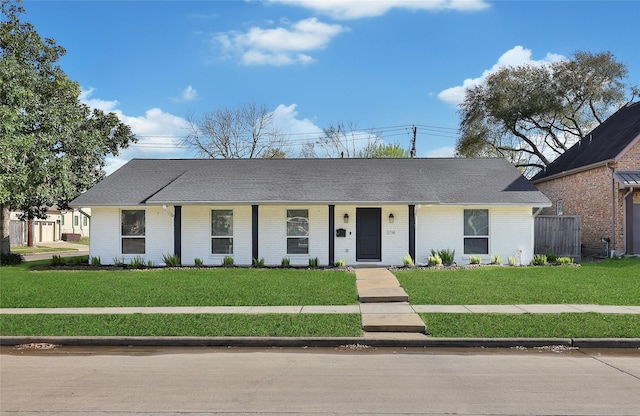 view of front of house featuring brick siding, covered porch, a front lawn, and a shingled roof