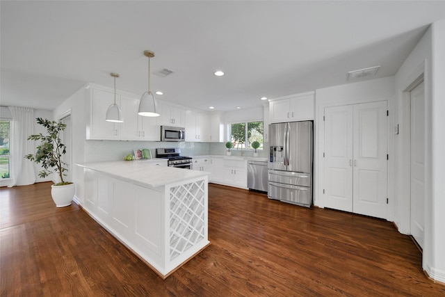 kitchen featuring dark wood finished floors, a peninsula, light countertops, and stainless steel appliances