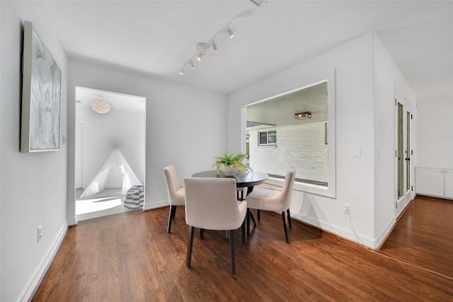 dining space with baseboards, wood finished floors, and track lighting