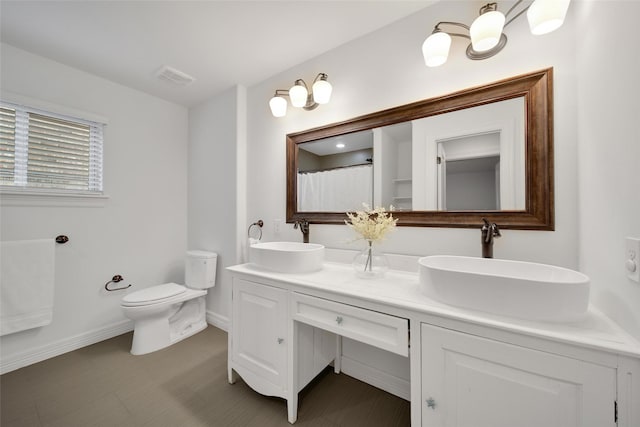 full bathroom featuring toilet, baseboards, visible vents, and a sink