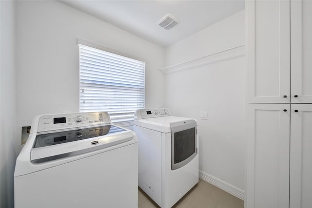 washroom with washer and clothes dryer, visible vents, cabinet space, and baseboards