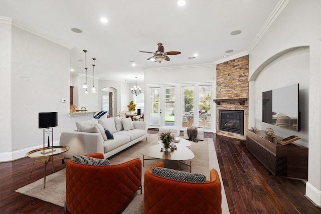 living room with arched walkways, a stone fireplace, ceiling fan with notable chandelier, ornamental molding, and hardwood / wood-style floors