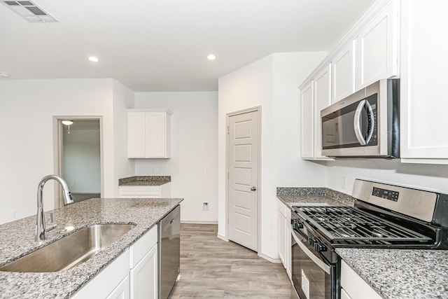 kitchen featuring light wood-style flooring, a sink, visible vents, white cabinets, and appliances with stainless steel finishes