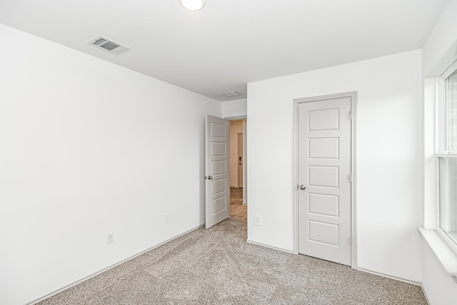 unfurnished bedroom featuring visible vents and light colored carpet