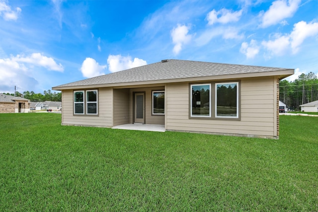 rear view of property with roof with shingles, a lawn, and a patio area