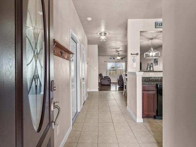 hallway featuring light tile patterned flooring, visible vents, and baseboards