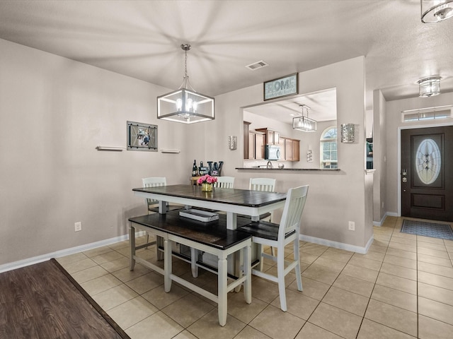 dining room featuring light tile patterned floors, a chandelier, visible vents, and baseboards