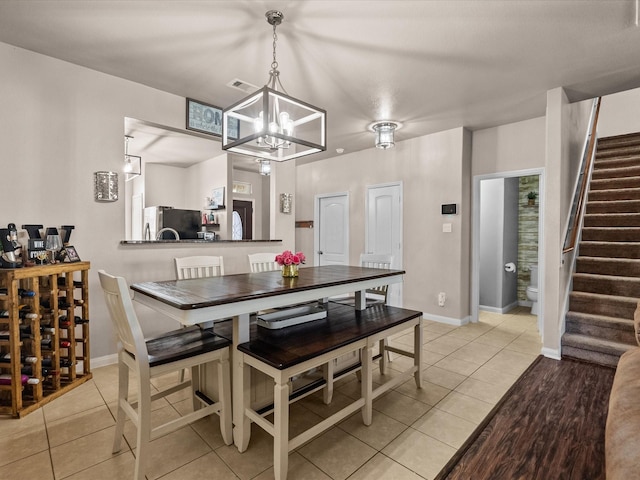 dining area featuring light tile patterned floors, baseboards, stairs, and visible vents