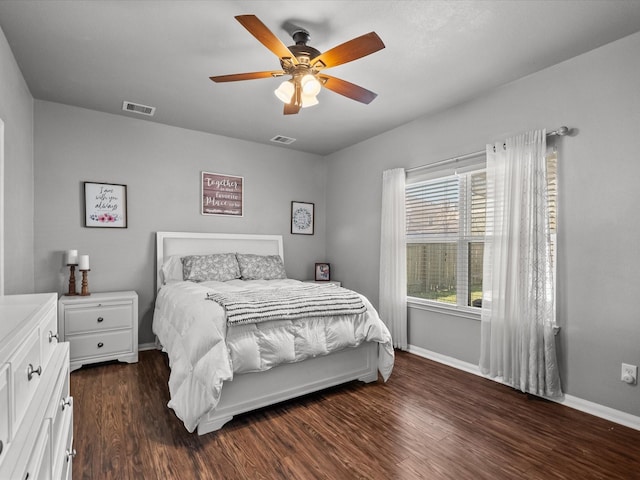 bedroom with dark wood-style floors, a ceiling fan, visible vents, and baseboards