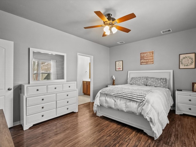 bedroom with dark wood finished floors, visible vents, and connected bathroom