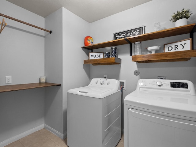 laundry area featuring light tile patterned floors, laundry area, washer and clothes dryer, and baseboards