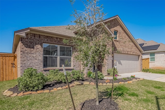 view of front facade with concrete driveway, brick siding, a front lawn, and fence