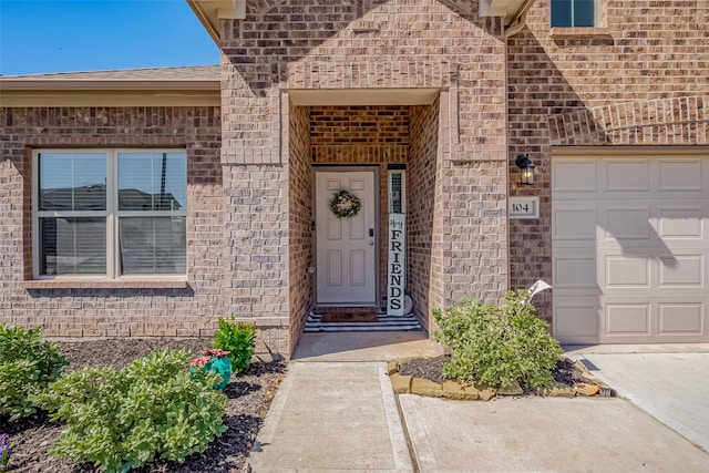 doorway to property featuring an attached garage and brick siding