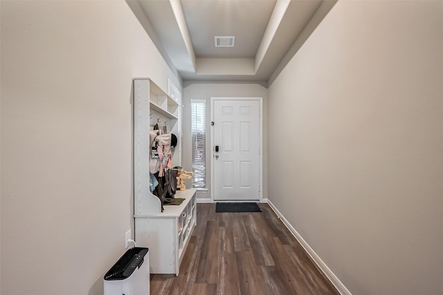 interior space featuring dark wood-style flooring, visible vents, a raised ceiling, and baseboards